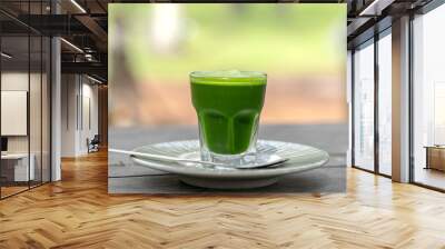 Wheat grass juice natural drink with fresh wheatgrass in glass on old wooden table background. Organic healthy organic green detox juice Wall mural