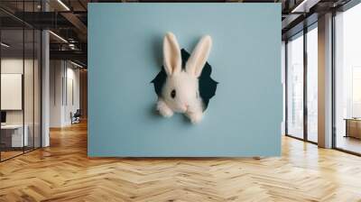 A cute rabbit peeking through a torn blue wall, showcasing a playful and imaginative scene Wall mural