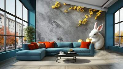 A white rabbit beside decorated eggs and spring blooms on a textured gray surface Wall mural