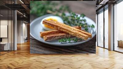 two bread sticks with eggs on a white plate with some herbs Wall mural