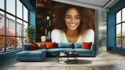 Young woman with curly hair smiling by a window in casual summer attire during daylight hours Wall mural