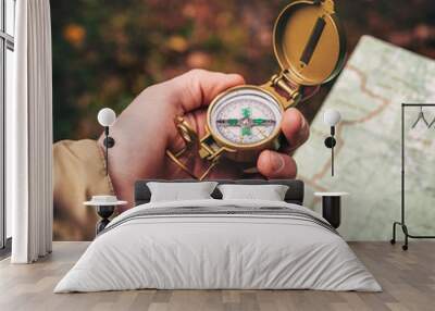 A man holds a compass and a paper map in his hand and is guided by the area, autumn forest, walk,hiking Wall mural