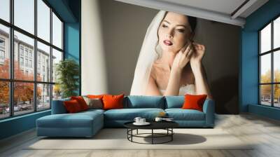 Beautiful young bride with makeup and hairstyle in bedroom, newlywed woman final preparation for wedding. Happy girl waiting groom. Portrait soft focus Wall mural