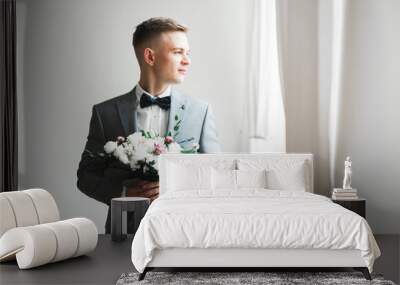 Happy handsome smiling groom posing with boutonniere Wall mural