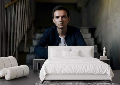 portrait of young man in a jacket sits on ladder Wall mural