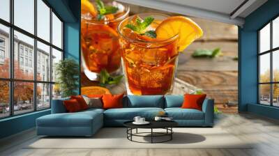 A refreshing cocktail recipe with a glass of iced tea, garnished with orange slices and mint leaves, served on a wooden table. Wall mural