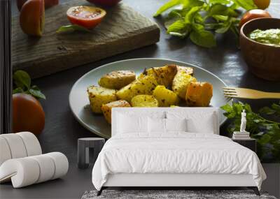 Baked potatoes, greenery sauce, fresh tomatoes, basil leaves and parsley on the kitchen table.  Wall mural