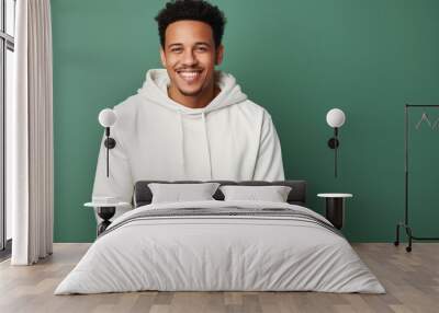 Young smiling african american man wearing blank white hoodie isolated on a green background. AI Wall mural