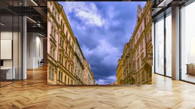 Yellow vintage houses on a narrow street in Prague, Czech Republic on an overcast day under heavy rain clouds. Copy space, bottom view Wall mural