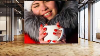 a series of photographs with a young woman in the winter forest. girl in a snowy park. in a red jacket with a cup in hand. winter walk in nature. Cold season. portrait, close-up Wall mural