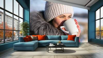 photo with a young woman in the winter forest. girl in a snowy park. in a red jacket with a cup in hand. winter walk in nature. Cold season, sunny day. portrait, drinking tea. close-up Wall mural