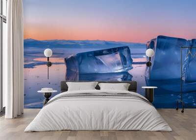 Ice on the lake, two large ice blocks of different shapes in front of each other, reflection, sunset, mountains in the distance, blue sky, closeup shot Wall mural