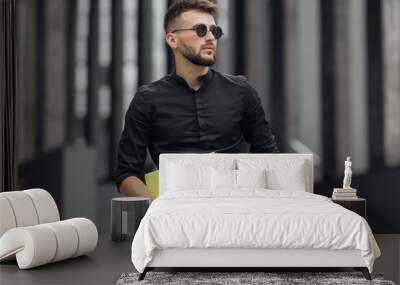 Bearded man in black dress in glasses with yellow folder
 Wall mural