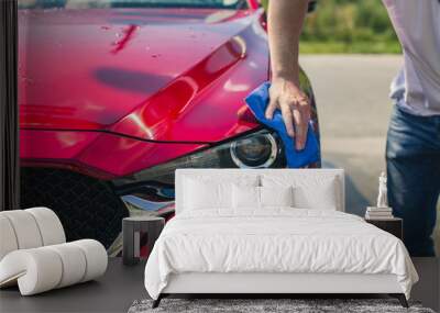 Car detailing - the man holds the microfiber in hand and polishes the car. Selective focus. Car detailing series : Worker cleaning red car.  Wall mural