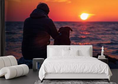 Loyal Companion: Man and His Faithful Dog Cuddling by the Colorful Ocean Sunset Wall mural