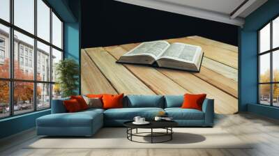 Open Bible book on a wooden table and black background. Wall mural