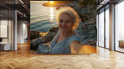 Senior woman takes selfie on sea sunset landscape background Wall mural