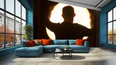 Silhouette of a man on the background of the lighting device. Wall mural