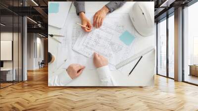 The team of architects is working on the sketches of the blueprints for the project. Engineers create a room design by drawing on paper. The builders are discussing at the desk. Wall mural