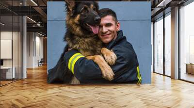 firefighter plays with a sheepdog, hugs, rejoices Wall mural