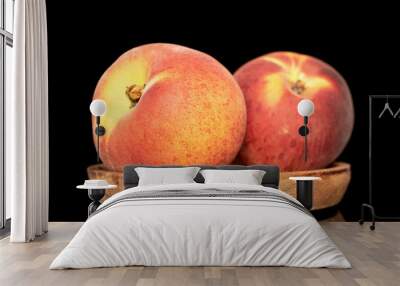 Two sweet organic peaches on a wooden saucer, close-up isolated on a black background. Wall mural