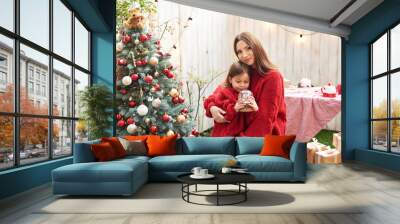 Christmas in July. Family woman mother and child daughter on the background of a Christmas tree
 Wall mural