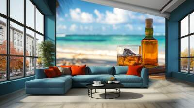 A bottle and glass of rum on a bar counter with a sandy beach and sea waves in the background. Whiskey or bourbon on a table with a tropical island landscape. Wall mural