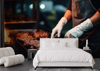 A man in an apron gloves and cook meat on a grill with fire in the backyard of the house in the evening. Wall mural