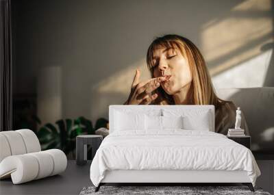 Attractive girl eating croissants in a bright room. Beautiful girl eating croissants with chocolate for breakfast Wall mural