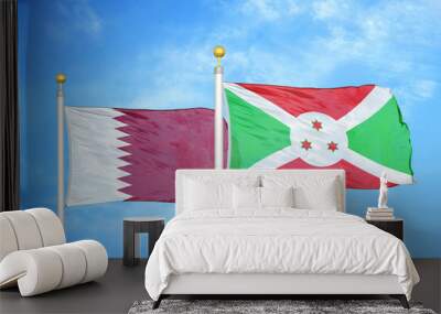 Qatar and Burundi  two flags on flagpoles and blue cloudy sky Wall mural