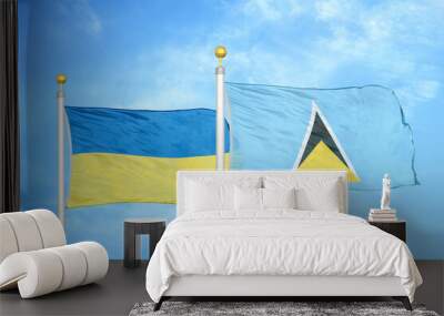 Ukraine and Saint Lucia two flags on flagpoles and blue sky Wall mural