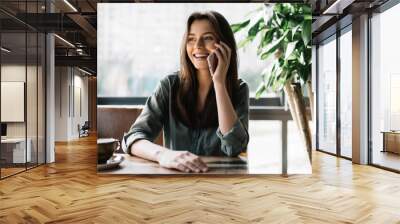 young beautiful woman using mobile phone in modern coffee shop. cute smiling businesswoman holding s Wall mural