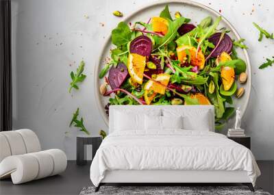 Beet and orange healthy salad with arugula, lamb lettuce, mini chard and pistachios, white kitchen table, copy space. Fresh useful vegan dish for healthy eating Wall mural