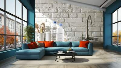 Bottles of clean water and sink on kitchen counter near white brick wall Wall mural