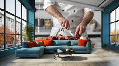 Chef cooking meat on wooden board on white table over white kitchen Wall mural