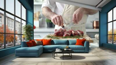 Chef cooking meat on wooden board on white table over white kitchen Wall mural