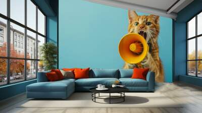 Funny red cat holds a yellow loudspeaker in its paws and screams on a blue background, a creative idea. Business and management, concept Wall mural