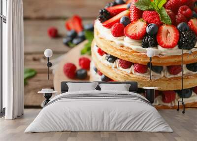 Tasty sponge cake with fresh berries and mint on wooden table, closeup Wall mural