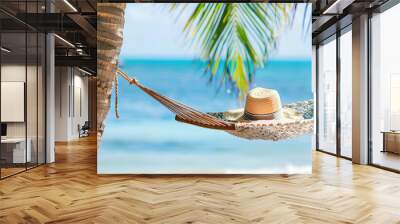 view of nice hammock hanging between two palms with some hat in it over blur ocean background sunny summer day Wall mural