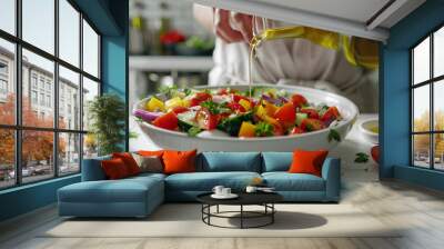 Woman adding olive oil to fresh vegetable salad on table Wall mural