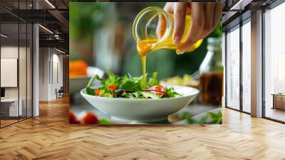 Woman hand pouring honey mustard dressing into bowl with fresh salad on table Wall mural