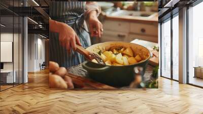 Woman putting peeled potato in pot at table in kitchen Wall mural