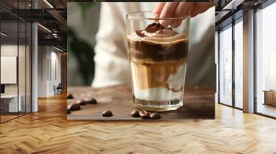 Woman taking glass of delicious dalgona coffee with chocolate from wooden table, closeup Wall mural