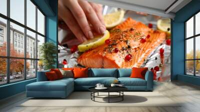 Woman wrapping tasty salmon with lemon and spices in aluminum foil at grey textured table, closeup Wall mural