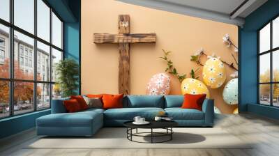 Wooden cross and painted Easter eggs on beige background Wall mural