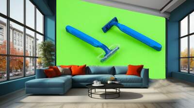 Two new blue plastic disposable razors with two blades and humid strip in transparent cover on blank green paper Wall mural