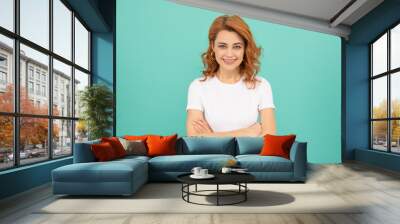 cheerful redhead girl with curly hair on blue background Wall mural