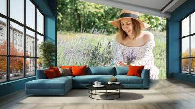 Young beautiful woman picking lavender flowers. Wall mural