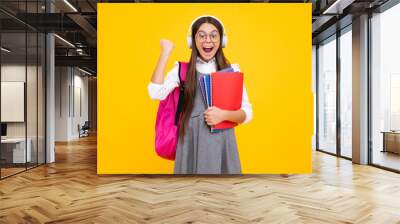 School girl, teenage 12, 13, 14 years old in headphones and books on isolated studio background. School kids with backpack. Excited teenager girl. Wall mural