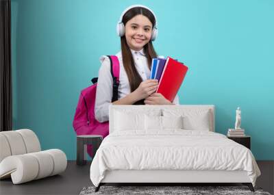 School girl, teenage 12, 13, 14 years old in headphones and books on isolated studio background. School kids with backpack. Wall mural